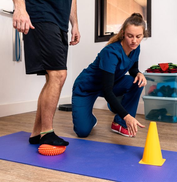 Stock photo of a man receiving help by physiotherapist professional woman.